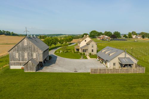 Hazy aerial view of a farmhouse and barn set among rolling farmland
