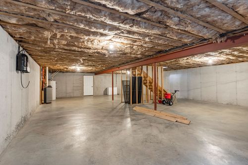 Open unfinished basement with a red support beam and staircase