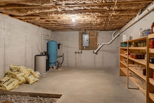 Basement storage room with a water heater, pressure tank and wood shelving