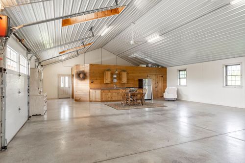 Vaulted pole barn interior with a wood-paneled kitchenette and dining area