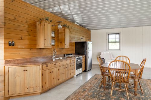 Kitchenette with knotty pine cabinets, stainless appliances and a dining table