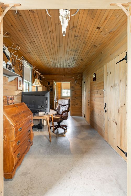 Knotty pine hallway with a roll-top desk, TV and mounted antlers