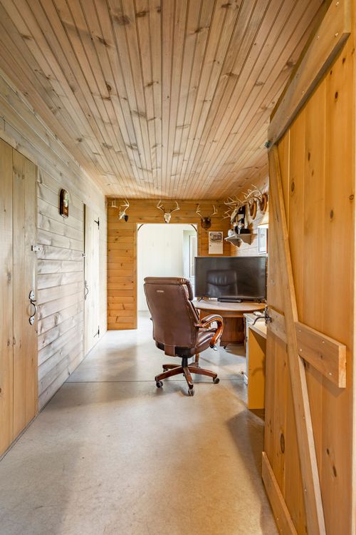 Knotty pine office hallway with a barn door, desk and mounted antlers