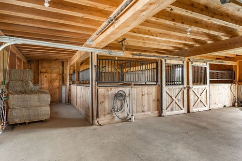 Barn aisle with horse stalls and stacked hay bales