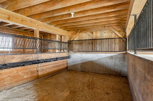 Close view of a wood-post horse stall with a grated front panel