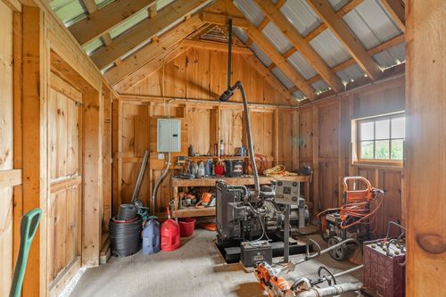 Utility room with a generator, electrical panels and wood plank walls