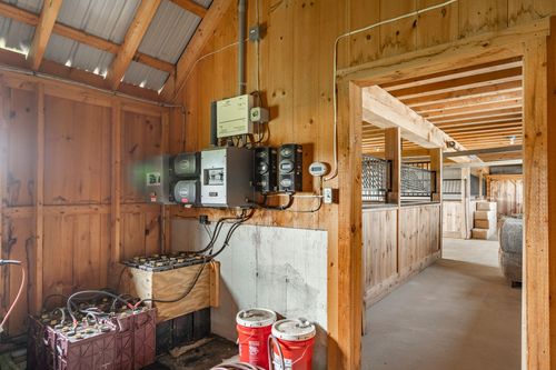 Barn utility room with electrical panels, batteries and concrete-and-wood walls