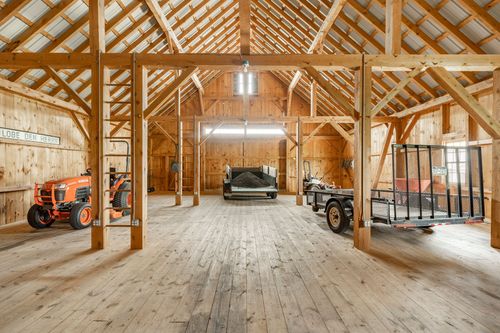Large barn interior with timber frame trusses and a parked tractor