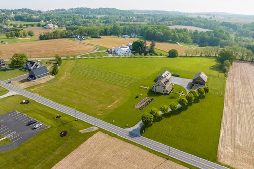 Aerial view of a farmhouse property beside a country road and parking area