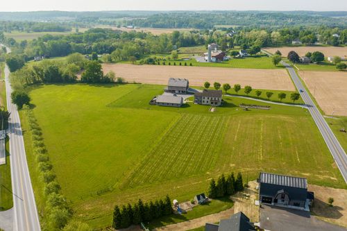 Aerial view of a farmhouse and barn among neighboring homes and open fields