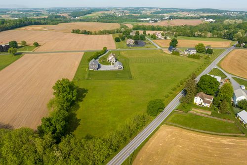 Aerial view of a farmhouse and barn beside a winding country road