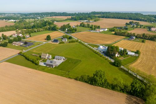 Aerial view of a farmhouse with vineyard rows and a barn in the distance