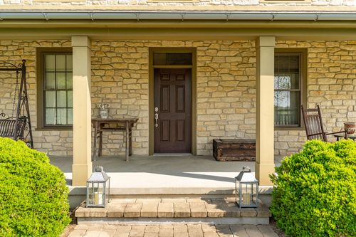 Front door of a stone farmhouse framed by columns and hanging lanterns
