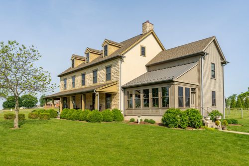 Rear exterior of a stone and stucco farmhouse with a sunroom addition