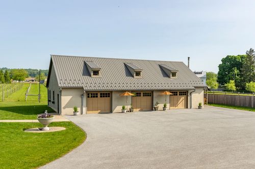 Exterior of a bank-barn-style four-car garage with dormer windows and cupolas