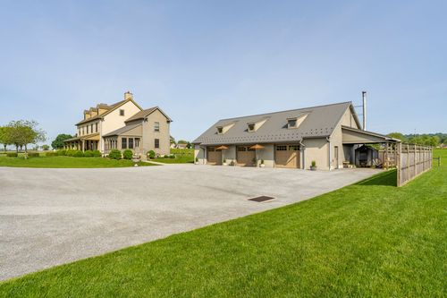 Stone farmhouse and matching detached garage viewed from the driveway