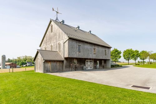 Weathered gray bank barn exterior with roof cupolas and a weathervane