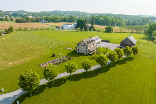 Aerial view of a farmhouse and barn amid golden-lit farm fields