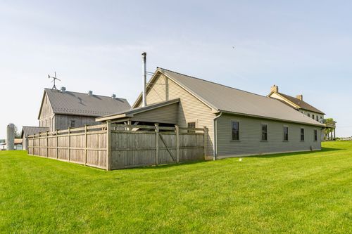 Side addition with a wood privacy fence beside the farmhouse and barn