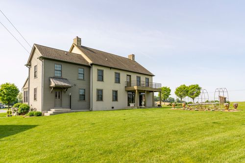 Rear exterior of a stone farmhouse with a second-story balcony