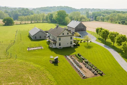 Aerial view of a farmhouse, guest building and barn arranged around a circular drive