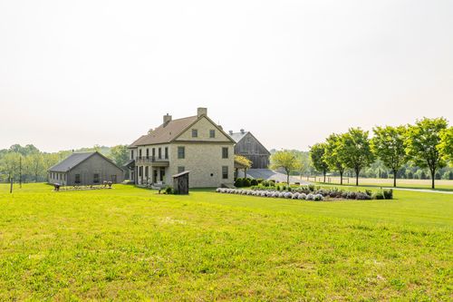 Farmhouse and barn exterior with a picnic table and garden bed on the lawn
