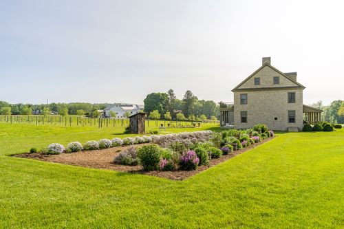 Flowering garden bed with the farmhouse and a small outbuilding beyond