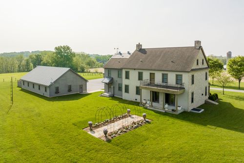 Aerial view of a farmhouse and barn nestled among rolling green fields