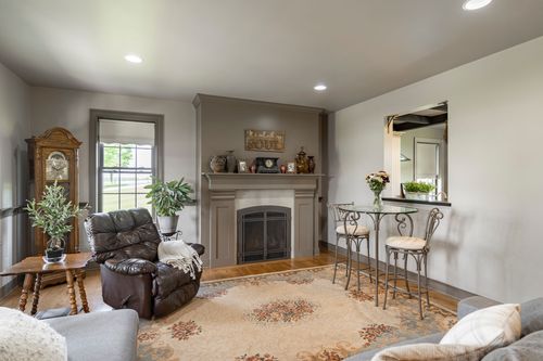 Living room with a leather recliner, area rug and glass bistro table by the fireplace