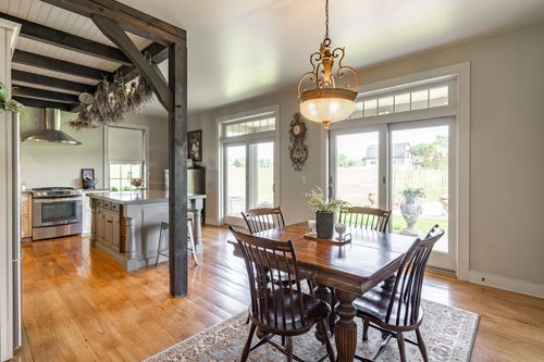 Farmhouse dining table beneath a chandelier with the kitchen visible beyond
