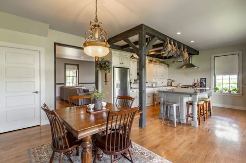 Dining area opens to a kitchen with a farmhouse table and hanging plant