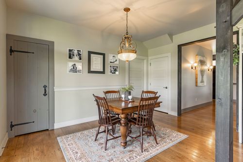 Dining room with a wood table, windsor chairs and a gallery wall of photographs