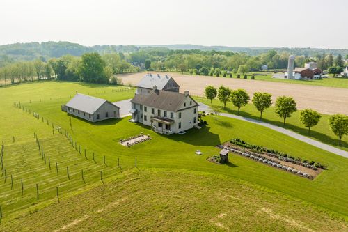 Aerial view of a farmhouse, barn, vineyard rows and formal garden beds