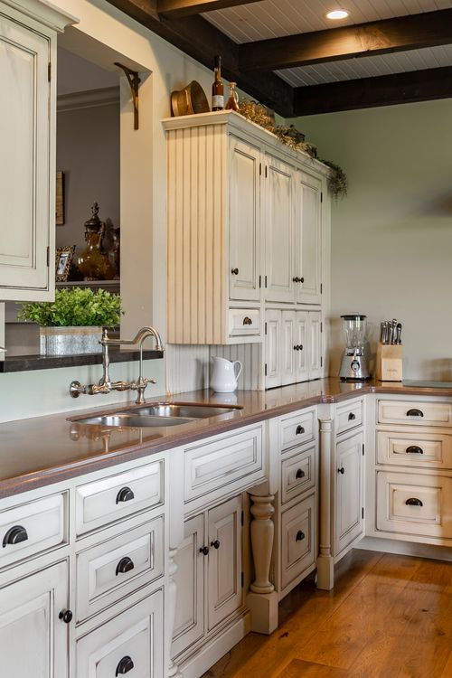 White farmhouse kitchen cabinetry with a copper countertop and vintage faucet