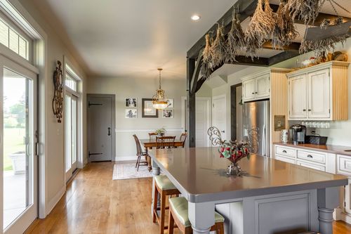 Farmhouse kitchen island with French doors and dried herb bundles overhead