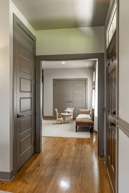 Hallway with paneled doors opening into a sitting room with wicker furniture
