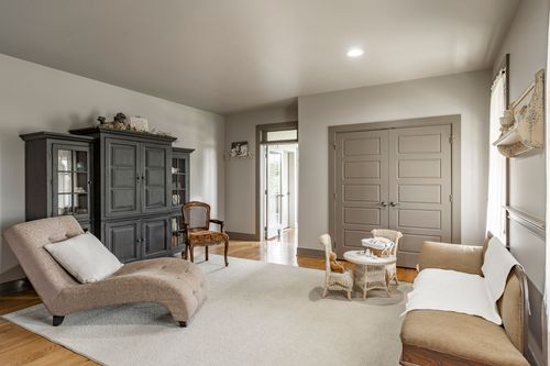 Sitting room with a dark armoire, chaise lounge and wicker accent chair
