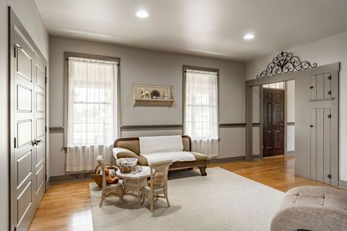 Sitting room with a loveseat, wicker table and two curtained windows