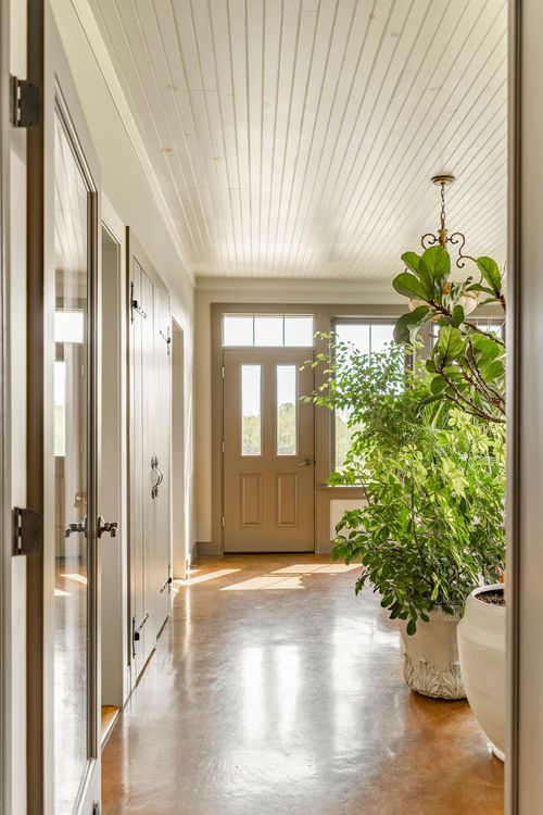 Foyer hallway with a glass-paneled front door and polished concrete floor