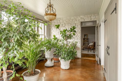 Sunroom corner with potted plants beside a stone wall and doorway
