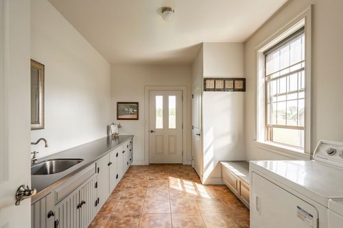 Mudroom with a stainless counter, sink and white cabinetry