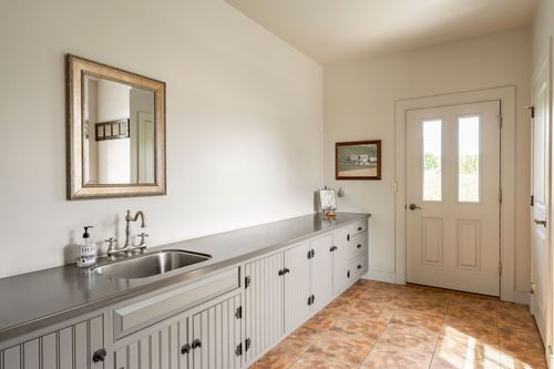 Mudroom with a wall-mounted mirror over a sink and a door to the outside