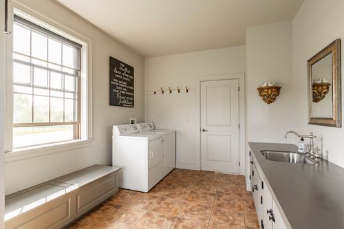 Laundry room with a white washer, window bench and coat hooks