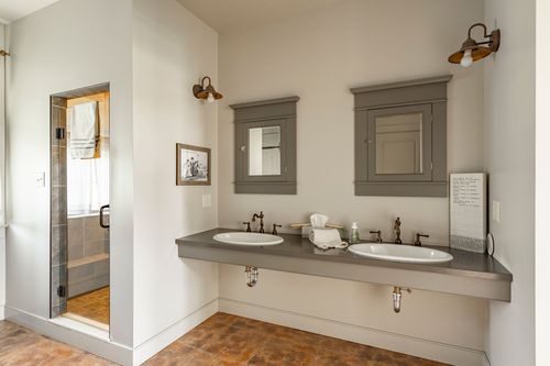 Double vanity bathroom with matching mirrored cabinets and wall sconces