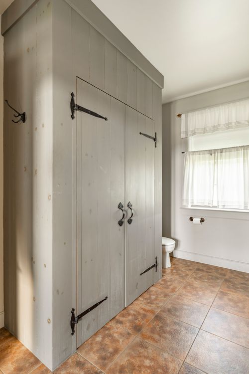 Bathroom with a tall board-and-batten linen cabinet and curtained window