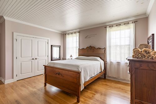 Bedroom with a wood bed, white linens and a beadboard ceiling