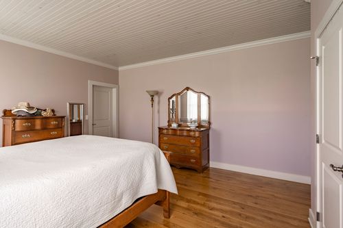 Bedroom with soft mauve walls, wood plank ceiling and an antique dresser with mirror