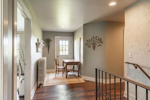 Upstairs hallway with sage walls, a dining nook visible through a doorway and dark wood floors