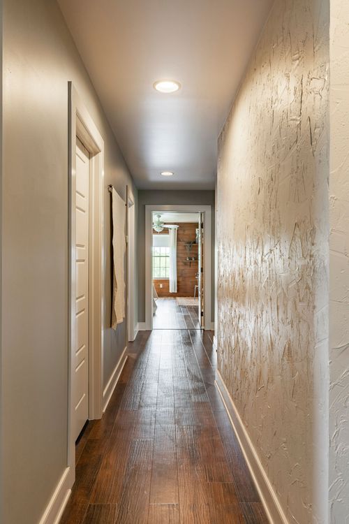 Narrow hallway with a textured plaster accent wall and rich wood-look flooring