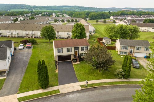 Aerial view of a split-level home with a driveway and mature shade tree